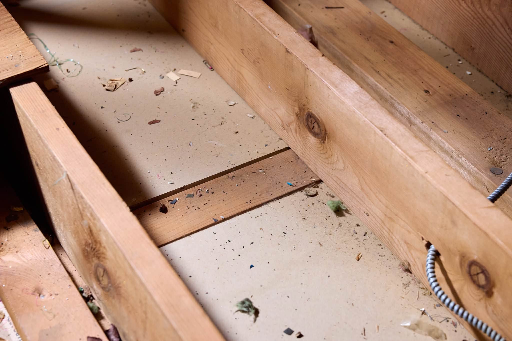 Attic floor with no insulation, open gaps between the joists and the drywall